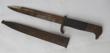 A bayonet with black grip and metal sheath.