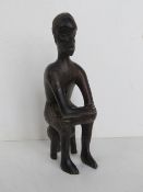 An African hardwood carving of a seated male approx 23cm high.