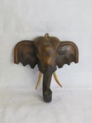 A carved wooden elephant head with wooden tusks.