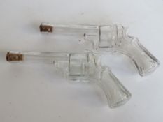 A pair of pressed glass whiskey flasks in the form of revolvers,