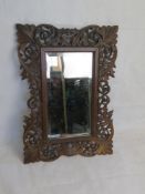 A Black Forest type carved wooden frame, good bevelled edge mirror within. Overall 37 x 52cm.