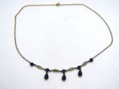 An early 20th century necklace set with blue paste stones and having filigree panels,