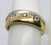 An 18ct white and yellow gold ring set with five round cut brilliant diamonds in rub over settings,