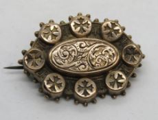 A Victorian rose metal brooch having Maltese cross design to outer circles and floral engraving to