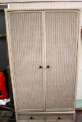 A wicker rattan covered two-door wardrobe, painted grey.
