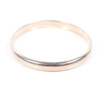 An early 20th century rose gold hollow-domed slave bangle. Stamped '9ct', 8.5mm wide, 10.