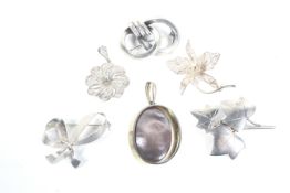 Four silver and white metal brooches and two pendants.