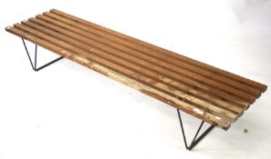 A mid-century industrial bench. On wire supports with wooden slates.