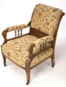 An Edwardian upholstered open armchair. On square tapering supports with casters.