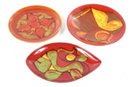 Three mid-century Poole Pottery Delphis plates. Comprising two circular and a shield shaped plates.