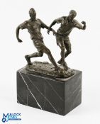 After Milo, a modern bronze sculpture of two footballers challenging for the ball, on a black marble
