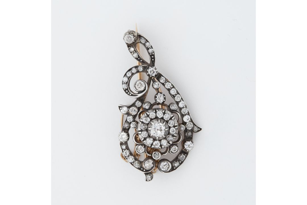 A Victorian 'scroll' design brooch set with old round cut diamonds, the largest diamond is approx.