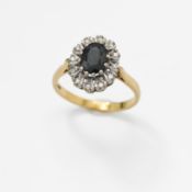 An 18ct yellow & white gold cluster ring set with a central oval cut ark blue sapphire, surrounded