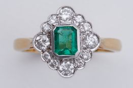 An 18ct yellow & white gold cluster style ring set with a central emerald cut emerald