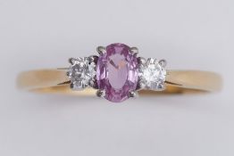 An 18ct yellow & white gold three stone ring set with a central oval cut pink sapphire