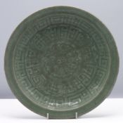 A celadon glazed saucer dish, Qing dynasty, 18th/19th century. Heavily potted and carved in low
