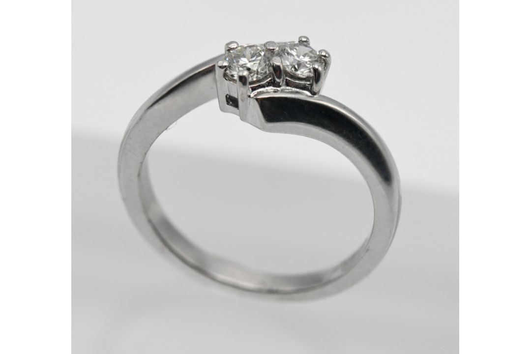 An 18ct white gold two stone diamond cross over ring, size K.