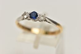 A YELLOW METAL THREE STONE RING, set with a central circular cut blue sapphire, flanked with