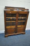 AN EARLY 20TH CENTURY OAK BOOKCASE, with two drawers, above two glazed doors, enclosing three