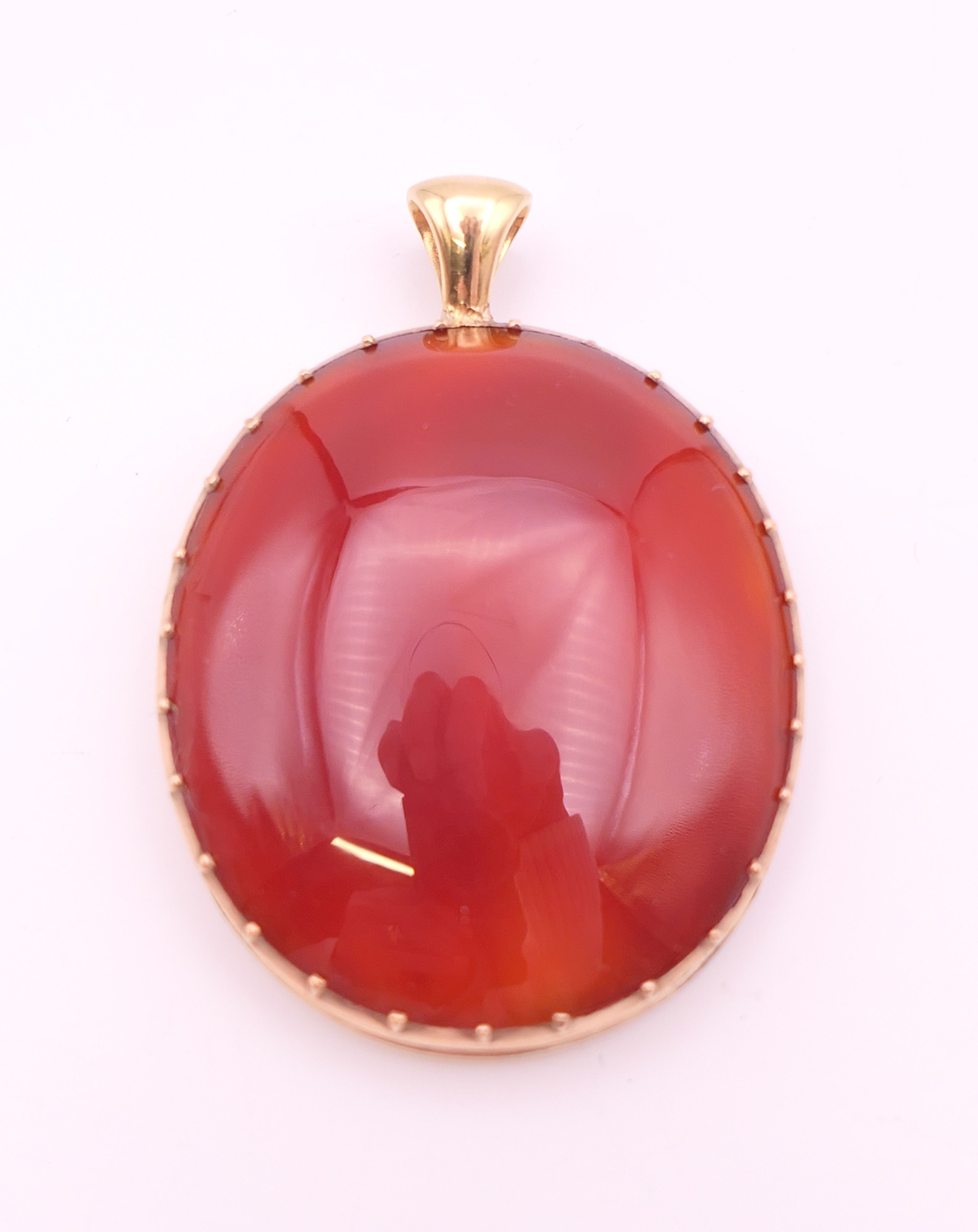 An unmarked 9 ct gold and carnelian pendant. 5 cm high. 17.9 grammes total weight.