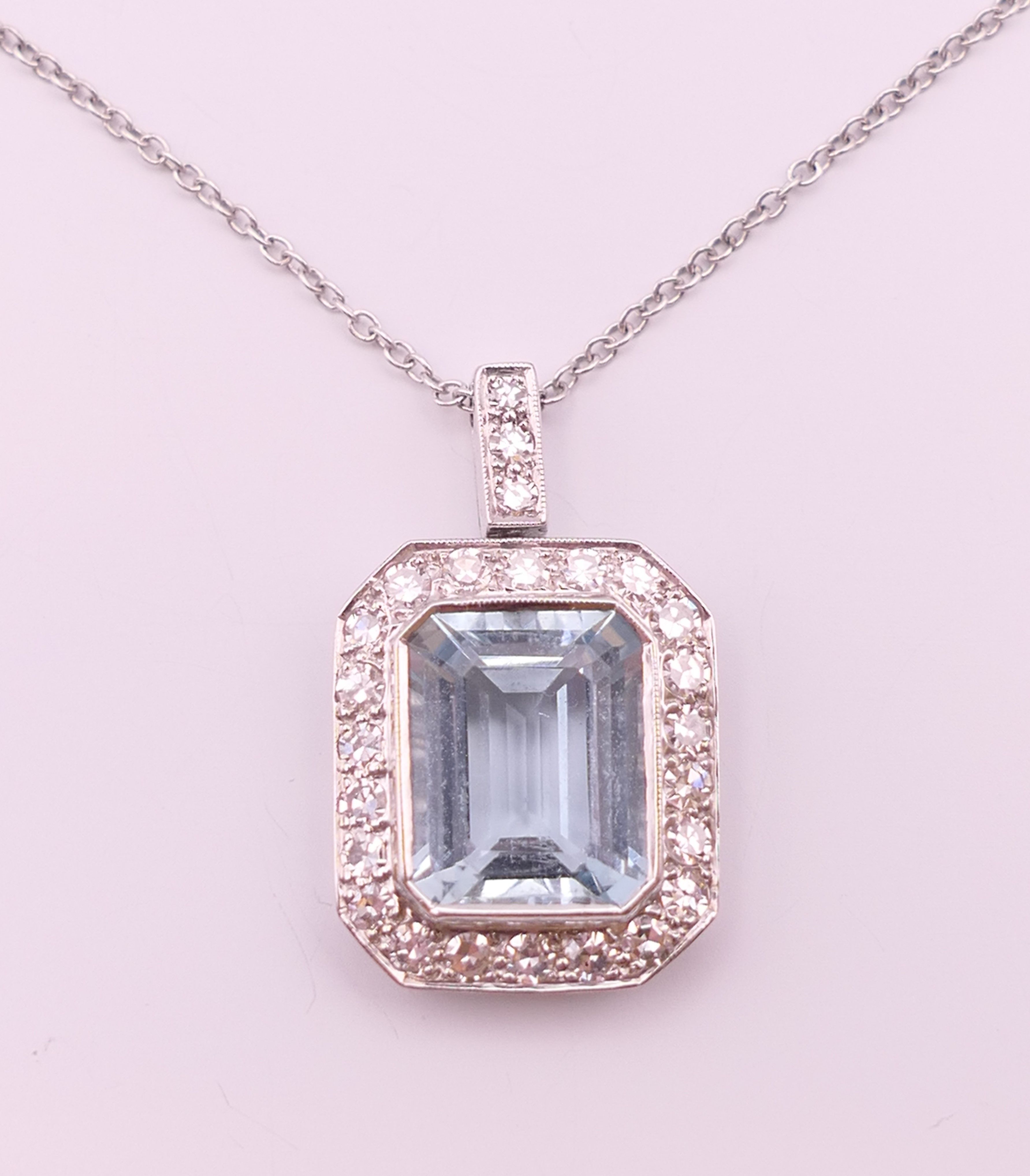 An 18 ct white gold emerald cut aquamarine and diamonds pendant on chain.