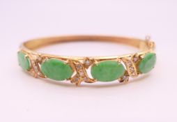 An 18 ct gold apple green faceted jade and diamond bangle form bracelet. 5 cm internal diameter.