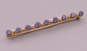 An antique unmarked gold (tested high carat) natural sapphire and seed pearl bar brooch, boxed.