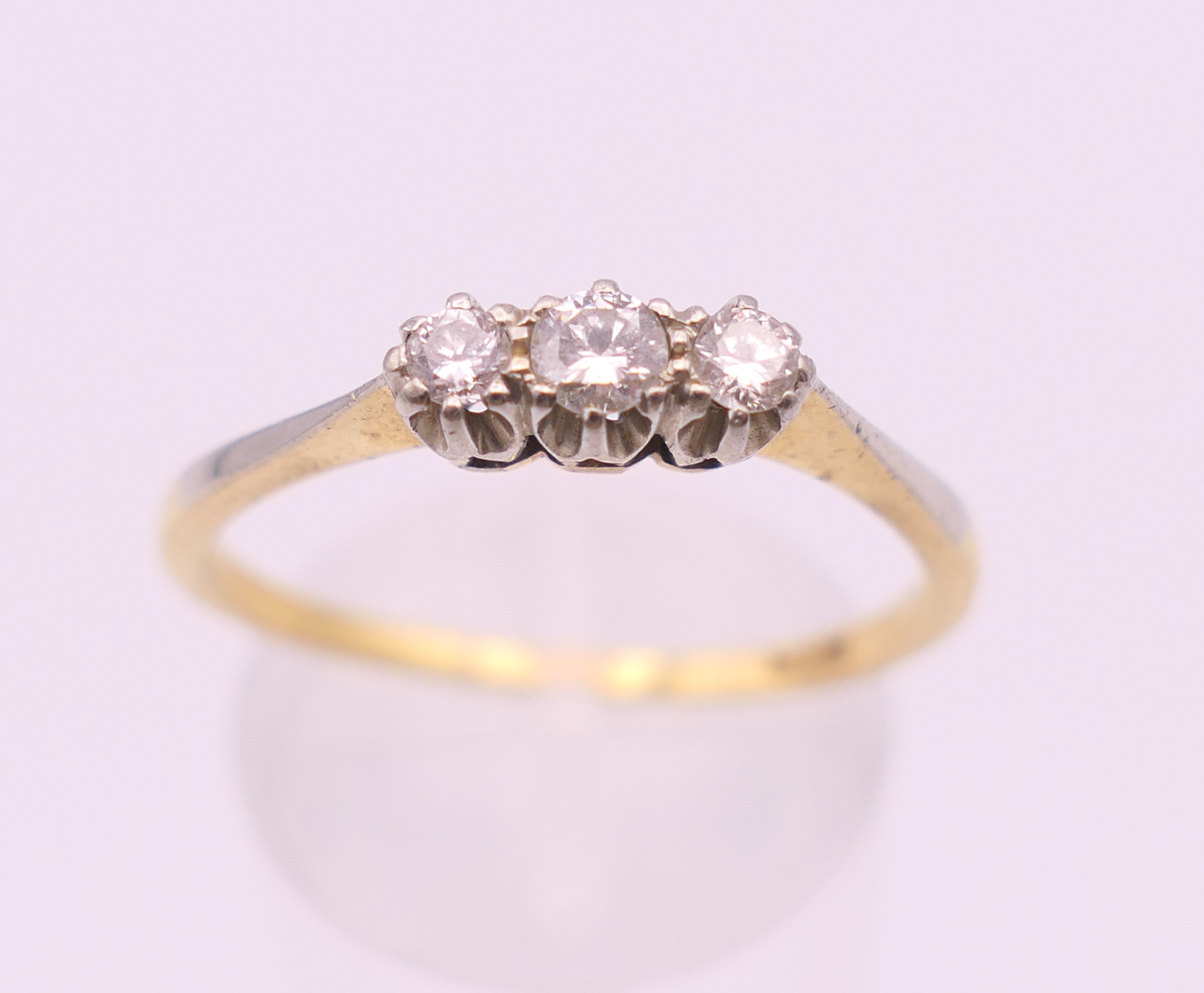 An 18 ct gold three stone diamond ring. Ring size R/S. 2.6 grammes total weight.