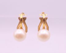 A pair of pearl earrings. Approximately 0.5 cm diameter.