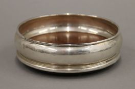 A silver coaster, hallmarked London 1986. 132.5 grammes total weight. 12.5 cm diameter.