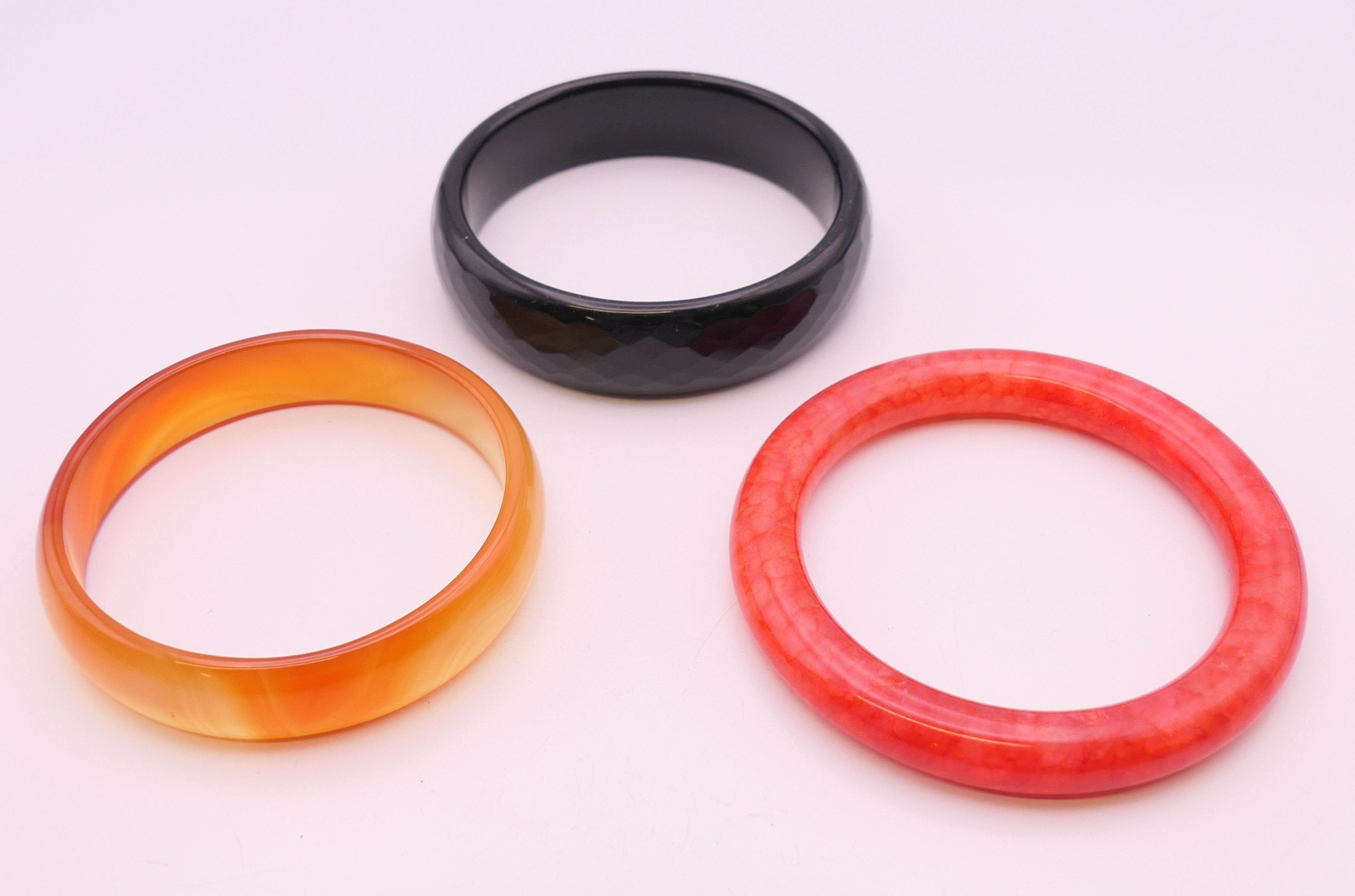 Three various bangles. Black and rust coloured bangles 6 cm internal diameter, red bangle 5.