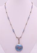 A silver and enamel locket on chain. Locket 2.5 cm diameter, chain 43 cm long.