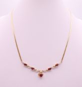 A 9 ct gold garnet and diamond necklace. Approximately 41 cm long. 6 grammes total weight.