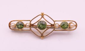 A 15 ct gold peridot and seed pearl brooch. 3.5 cm long. 3 grammes total weight.