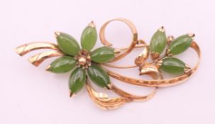 An 18 K gold and jade floral spray brooch. 7 cm long. 11.5 grammes total weight.