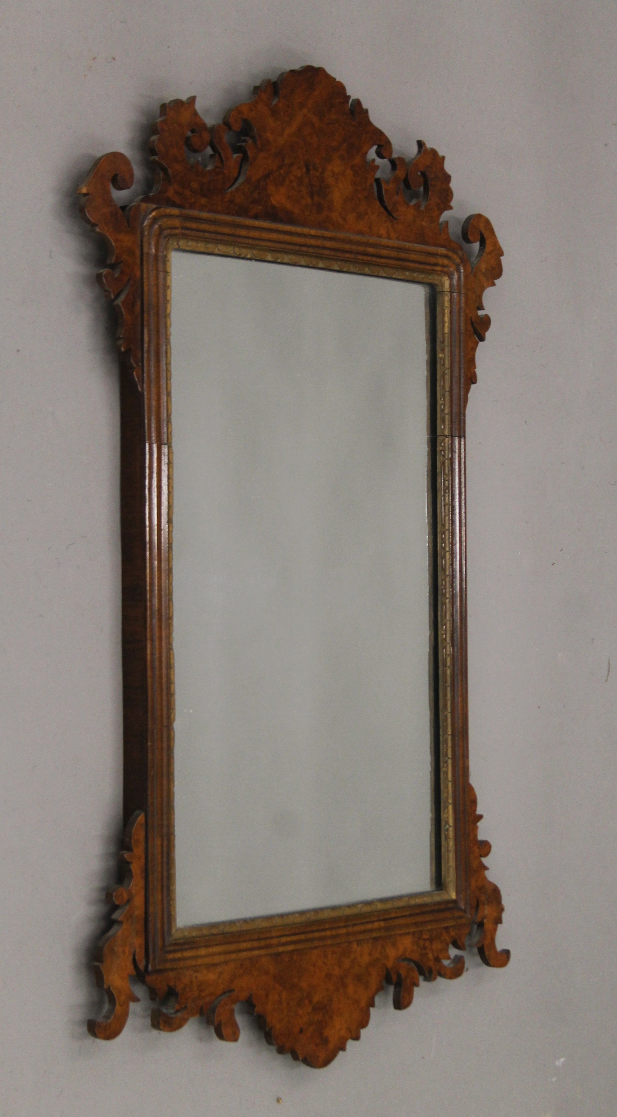 A George III style walnut and parcel gilt wall glass. 85 cm high.