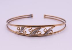An unmarked gold diamond set bangle form bracelet. 6.5 cm internal diameter. 5.