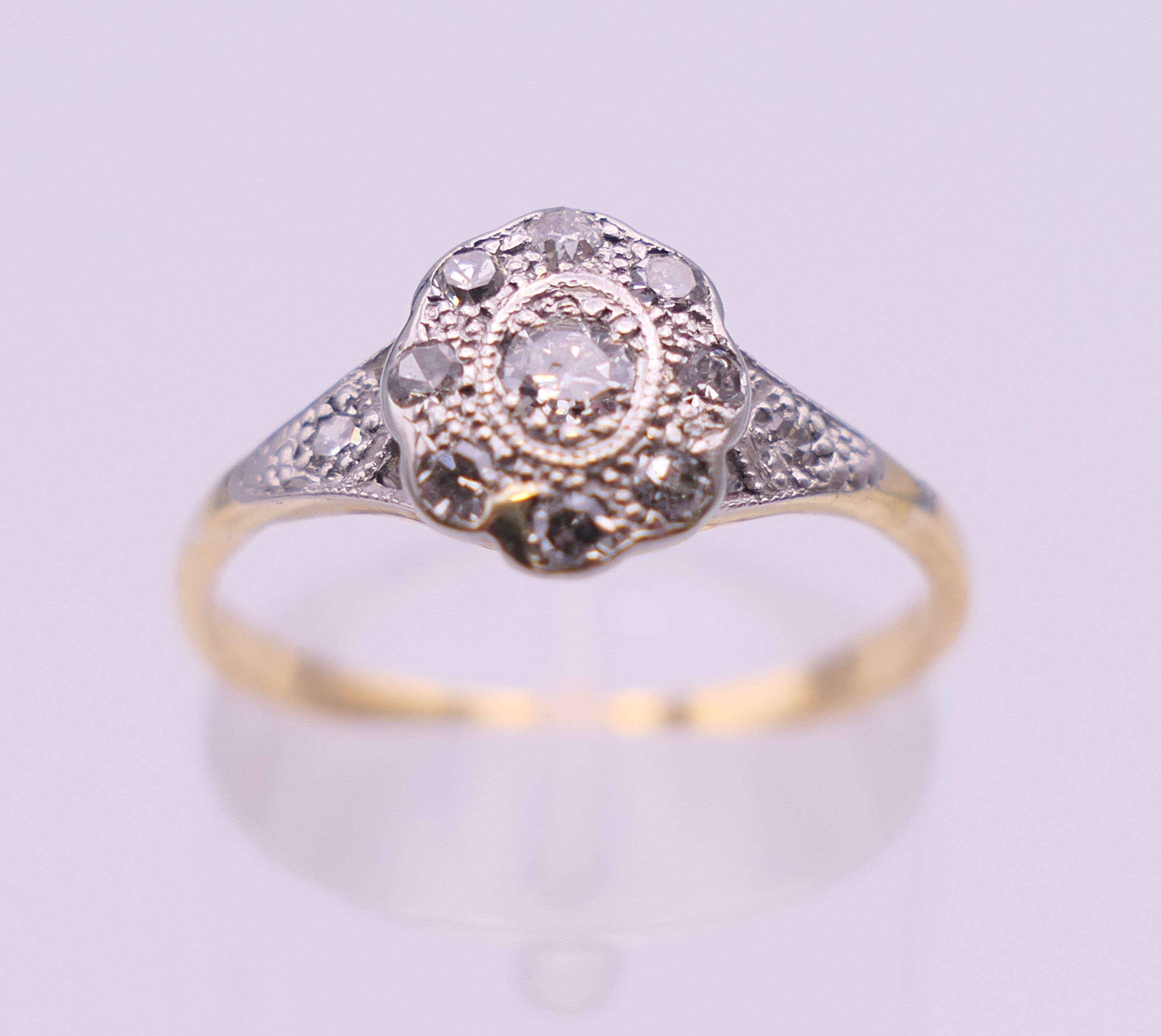 An Edwardian 18 ct gold oval diamond cluster ring. Ring size M. 2.3 grammes total weight.