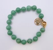 A Chinese jade bead bracelet with 14 K gold clasp. 20 cm long.