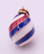 A 14 ct gold Russian enamel striped egg. 1.5 cm excluding suspension loop.