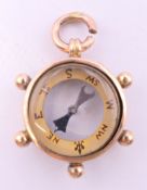 A 9 ct gold fob compass formed as a ship's wheel. 2.5 cm high. 5.6 grammes total weight.