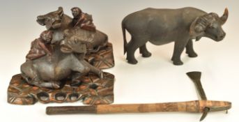 A pair of Chinese wooden carving of water buffalo with figures on their backs, on wooden bases,