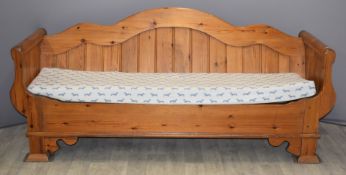 Pine sofa with serpentine sloping back, scrolling arms and lift out cushion decorated with