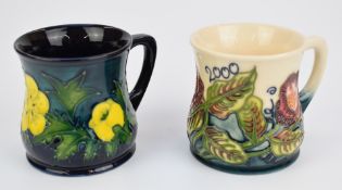 Moorcroft mug decorated in the Buttercup pattern and a year 2000 mug, both 9cm tall