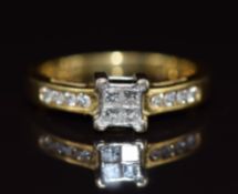 An 18ct gold ring set with four princess cut diamonds and further round diamonds to the shoulders,