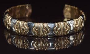 A 9ct gold bi-coloured bangle made up of puzzle sections, 19.7g