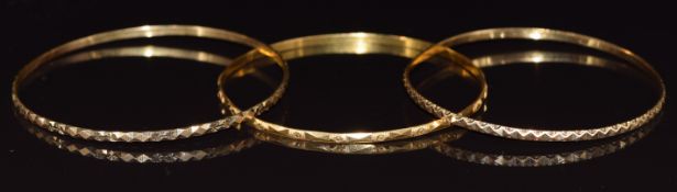 A 21ct gold bangle (7.1g), and two yellow metal bangles marked FJ18, 15.5g