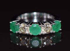 An 18ct white gold ring set with two diamonds, each approximately 0.38ct and three emeralds each