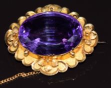 An 18k gold brooch set with a large oval cut amethyst with a floral border, 11.7g