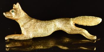 A yellow metal fox brooch with textured decoration and glass eyes, 16.9g